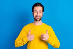 Portrait of attractive cheerful brunet guy showing thumbup ad agree isolated over bright blue color background