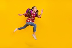Photo of funky cute schoolgirl wear checkered shirt running fast jumping high isolated yellow color background