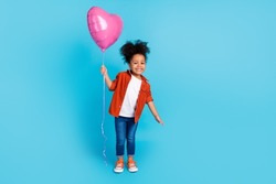 Full length photo of cheerful cute little lady receive birthday present hold heart shaped balloon isolated on blue color background