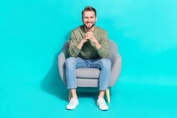 Photo of positive cheerful man sit armchair hold hands beaming shiny smile wear pullover isolated blue color background