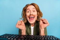 Portrait of attractive funky crazy cheerful guy geek using computer having fun isolated over pastel blue color background