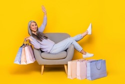 Photo of funny shiny lady pensioner dressed pullover sitting cozy chair rising bargains isolated yellow color background