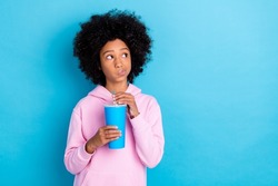Photo of young girl look empty space curious unsure think drink cola isolated over blue color background