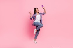 Full body photo of young brunette lady jump do selfie wear shirt jeans shoes isolated on pink background