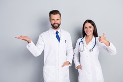 Photo of happy smiling two docs dressed white coats showing thumb up arm empty space isolated grey color background
