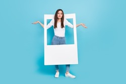 Full size photo of funny girl with white frame shrug shoulders not happy with photoshoot isolated on blue color background