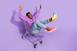 Full length body size view of attractive carefree cheery guy riding cart having fun isolated over vivid violet lilac color background