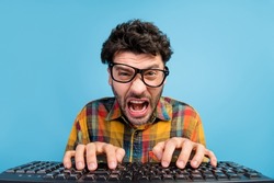 Photo of angry brunet guy type keyboard wear eyewear checkered shirt isolated on blue color background