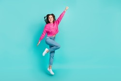 Full size photo of gorgeous cute woman with curly hairdo wear pink sweater jeans raise fist fliying isolated on turquoise color background