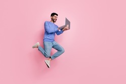 Full length photo of funny pretty guy dressed blue pullover jumping high typing modern device isolated pink color background