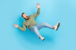 Full size photo of handsome young man frightened falling down slipping dressed stylish khaki outfit isolated on aquamarine color background