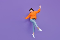 Full body photo of stunning young girl dancing enjoy party weekend dressed stylish orange knitted look isolated on purple color background