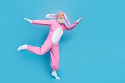 Full size photo of funky optimistic glad elderly pensioner wear pink bunny costume flying dancing isolated on blue color background