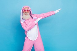 Portrait of funky optimistic elderly pensioner wear pink bunny costume indicating empty space have fun isolated on blue color background