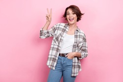 Photo of young charming business woman wear plaid trendy shirt with jeans belt show v-sign peace symbol isolated on pink color background