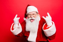It's party time! Holly jolly swag x mas and noel!  Cool funny playful naughty grandfather with sticking tongue, comic grimace, fooling around isolated on red background, shows rock gesture