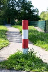 Crossroads. Red and white pole marking the intersection of a path and a road