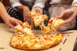 hands of colleague or friends eating pizza After a long meeting at office. They are having party at home, eating pizza and having fun. leisure, food and drinks, people and holidays concept 