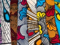 African wax fabric lined up at various angles with notions about n a bright background.