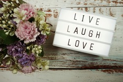 Live Laugh Love word in light box flat lay on wooden background