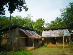 Poor Man House, Bangladeshi Poor Man House Made By Iron, Soil And Bamboo Fluit. Picture Highlights The Poverty Of Bangladeshi People. There Is A Cloudy Sky Background And Bettle Nut Trees. 