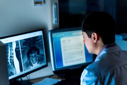 Radiologist sitting at computer in office. X-ray picture on screen. Healyj care concept.
