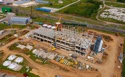 Large plant surrounded by green nature. Construction of the manufacturing in the countryside in summer. Modern industrial complex on field. Aerial view
