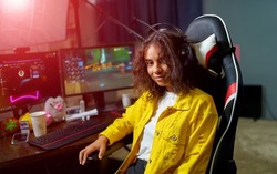 Teenage girl playing video games and sits in hi -tech room with modern computer and big monitors. Closeup.