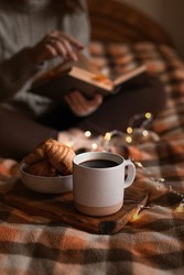 cozy autumn evening: girl, coffee, book and croissants