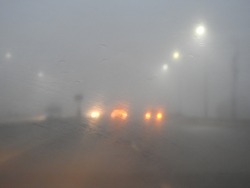 Poor visibility on the road due to heavy mist and fog early in the morning on the highway. slow-moving cars in heavy smoke and dangerous traffic in bad weather and slippery asphalt, blurry background