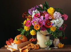 Still life with a bouquet of cultivated flowers, pumpkins and berries. Autumn still life.