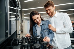 Young couple choosing new gas stove in home appliances store