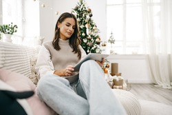 Beautiful woman relaxing on the sofa with digital tablet at Christmas
