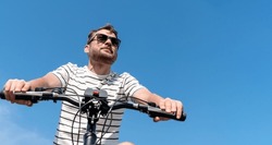 Low angle view man riding his bike in summer on background of blue sky.