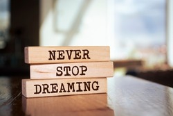 Wooden blocks form the words 'Never stop dreaming' on blur background.