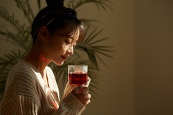 A young Asian woman relaxing at home drinking fruit tea