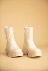 Product photo: beige female boots on beige background.