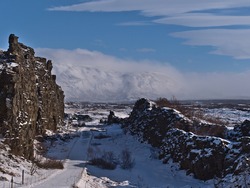 Stunning view of famous Almannagjá gorge in Þingvellir national park, Golden Circle, Iceland, a crack of Mid-Atlantic Ridge with steep cliffs, with snow-covered hiking path in winter season.