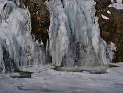 Closeup view of frozen rocky Kirkjufellsfoss water fall near Grundarfjörður on Snæfellsnes peninsula, western Iceland in winter with snow, ice formations and icicles.