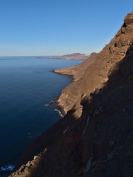 Stunning view of the western coast of island Gran Canaria, Canary Islands, Spain with steep cliffs above the Atlantic sea in the afternoon sun near La Aldea de San Nicolas in winter.