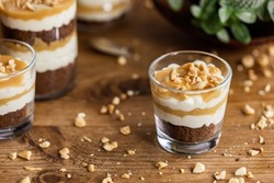 Caramel toffee cream peanut layered dessert in a glass jar on a wooden background	