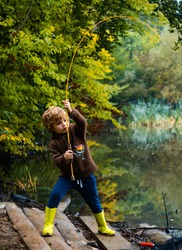 Little boy fisherman fishing in a lake with a fishing rod. Excited kid fishing on weekend