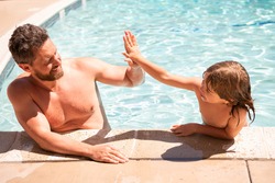 Father and son swimming in pool, summer family. Child with dad playing in swimmingpool. Family time. Summer vacation. Pool party.