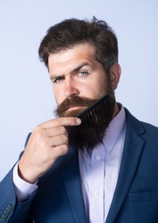 Closeup of a young man styling his long beard with a comb. Care beard. Bearded man with beard, bearded gay. Barbershop concept. Mustache men.