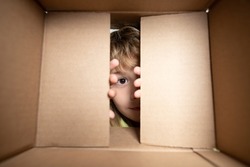 Happy child with cardboard box, unpacking parcel from internet store. Kids client satisfied with fast delivery service. Child with open box. Close up eyes looking.