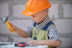 Portrait of little builder in hardhats with instruments for renovation on construction. Builder boy, carpenter kid with builder tools set. Kids builder and repair.
