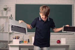 Bad boy student in opposition distance education. Angry kid broken online laptop at school. Smashing damaged computer technology. Kids problem with remote learning in classroom.