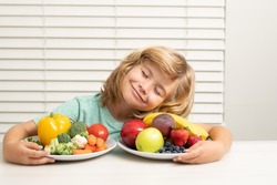 Fruits and vegetables. Schoolkid eating breakfast before school. Portrait of child sit at desk at home kitchen have delicious tasty nutritious breakfast.