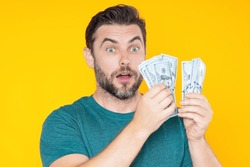 Man holding cash money in dollar banknotes on isolated yellow background. Studio portrait of business man with bunch of dollar banknotes. Dollar money concept. Career wealth business. Cash dollar.