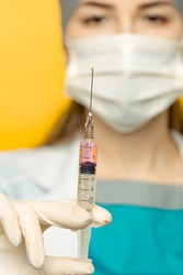 woman doctor (or nurse) look syringe needle isolated on yellow background